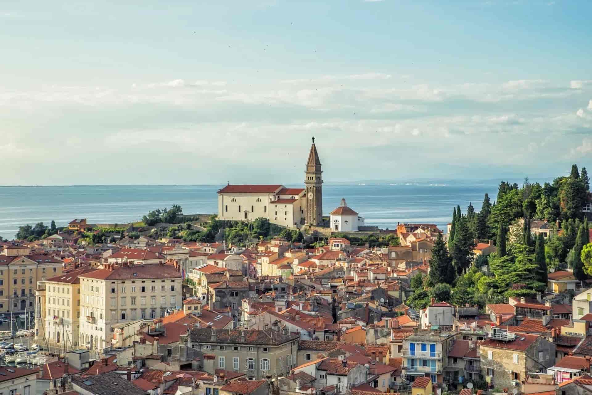 Piran coastal town with terracotta roofs and St. George's Parish Church overlooking the sea.