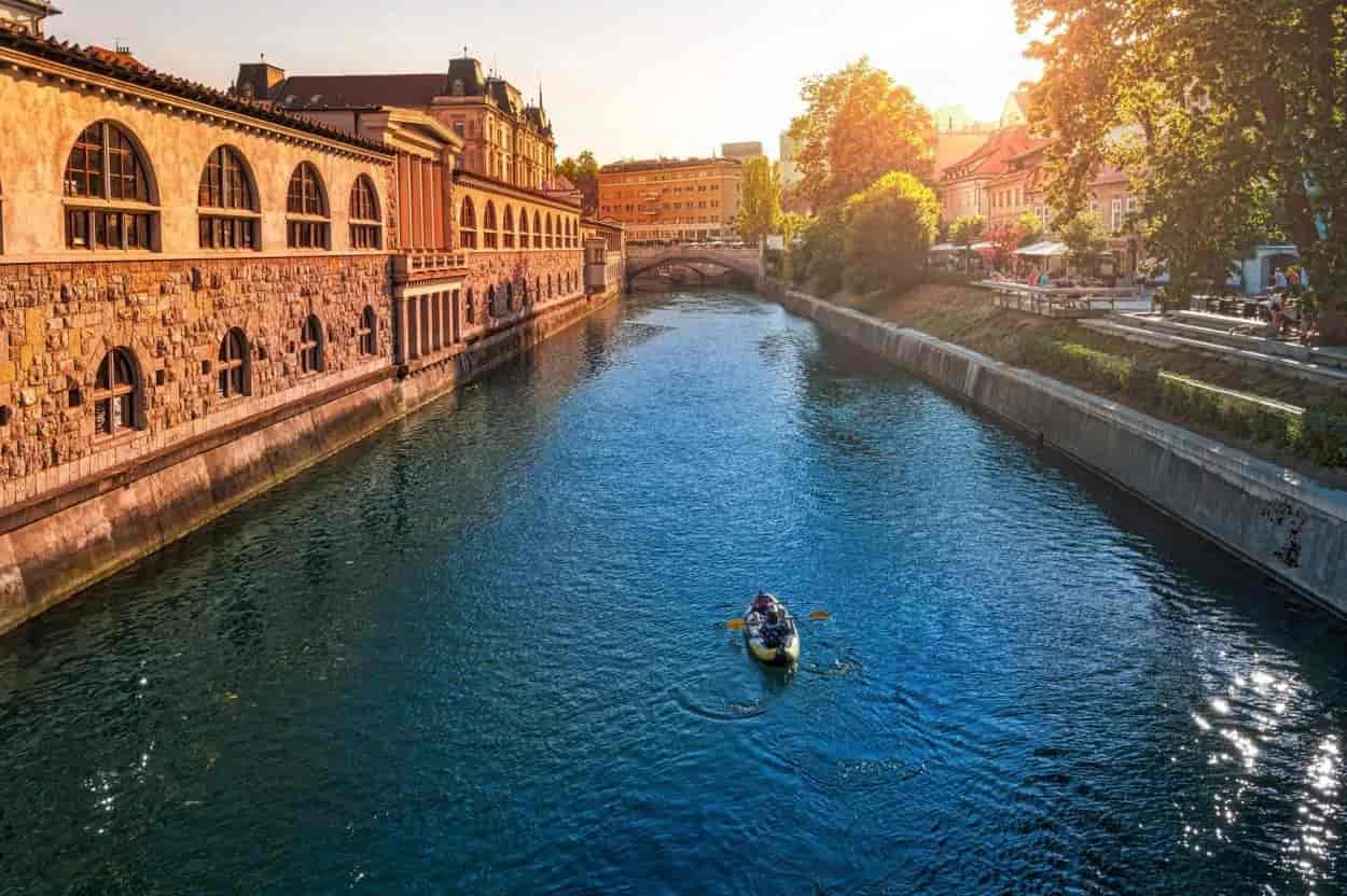 Canoeing on the Ljubljanica River by the stone City Market building in Ljubljana.