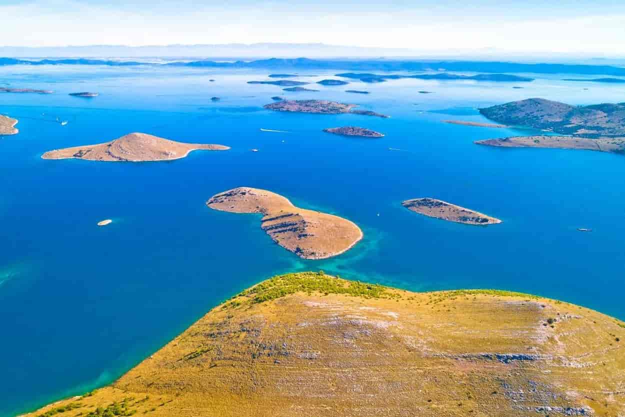 Aerial view of arid islands scattered across bright blue sea waters in Kornati National Park.