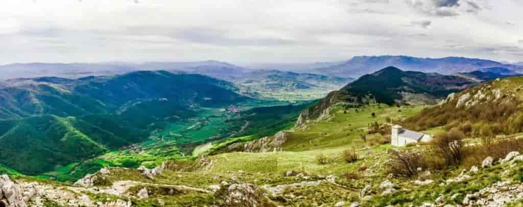 Vipava Valley, Slovenia landscape with green hills, distant mountains, and a small white church.