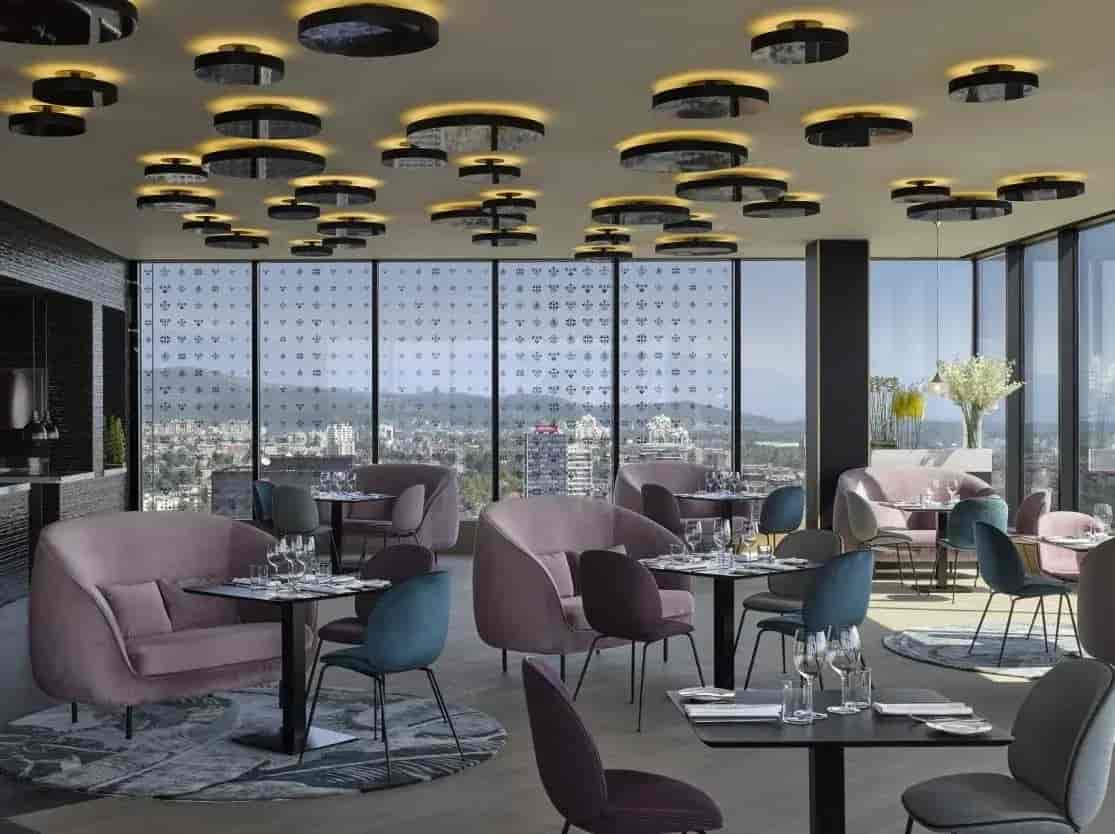 Dining room with plush seating, black tables, and city view through large windows at InterContinental Hotel B.