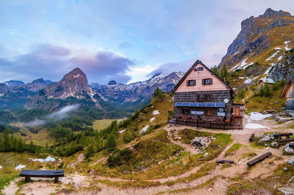 Wooden mountain lodge on hillside overlooking valley and rugged peaks, Vodnik Lodge.