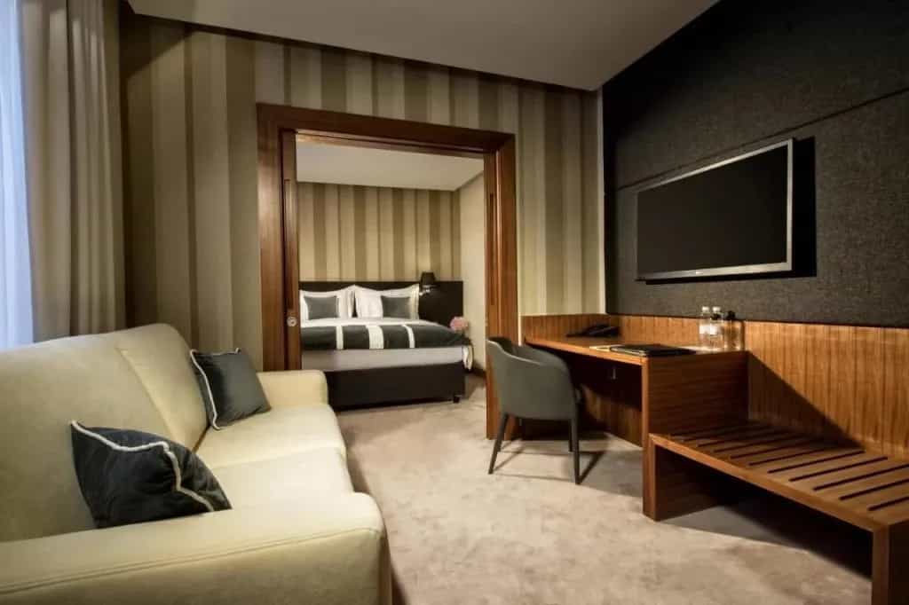 Hotel Slon suite with living area, desk, and view into a separate bedroom.