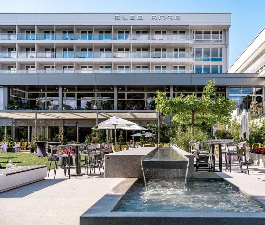 Hotel Bled Rose building exterior with outdoor patio seating and modern water feature