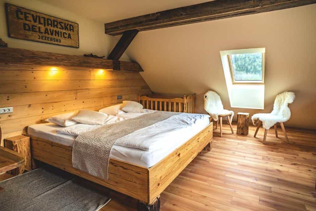 Attic bedroom with wooden bed, sheepskin chairs, and sign mentioning Jezersko