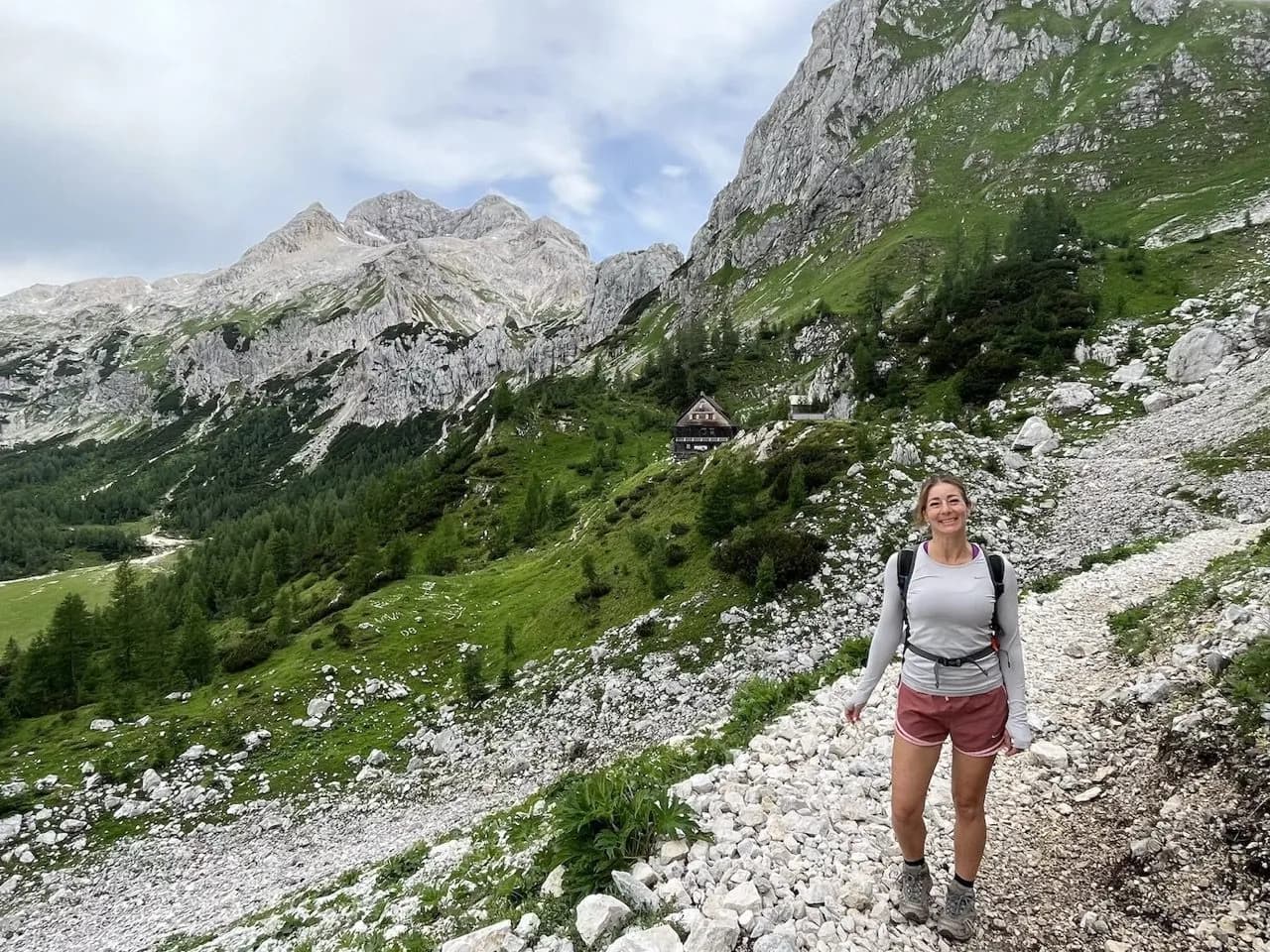 Hiker on rocky trail near Vodnik Hut with Triglav mountains in the background