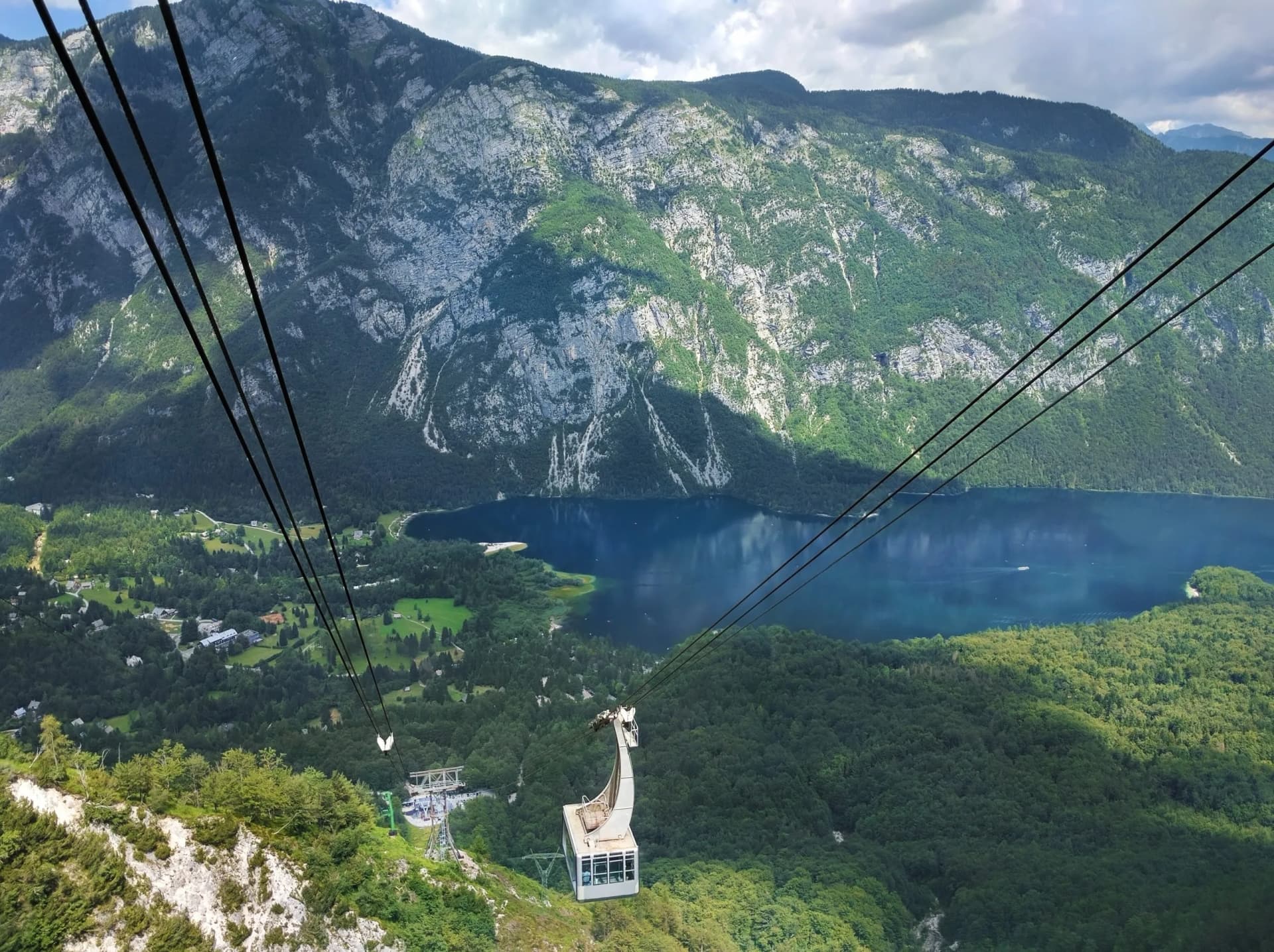 Cable car ascending over lush mountains toward Vogel, overlooking a dark blue lake.
