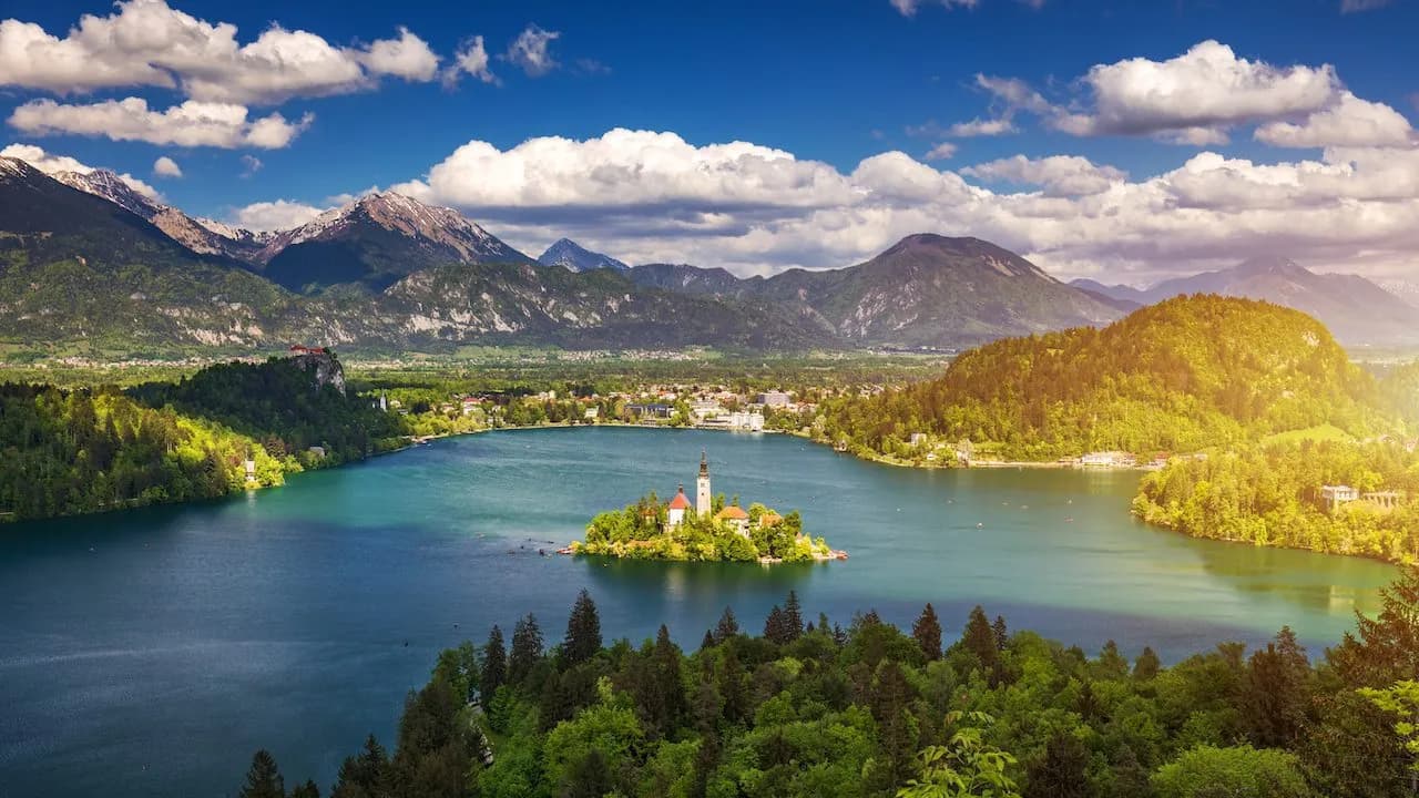 Panoramic view of Lake Bled island church with Julian Alps and green forests