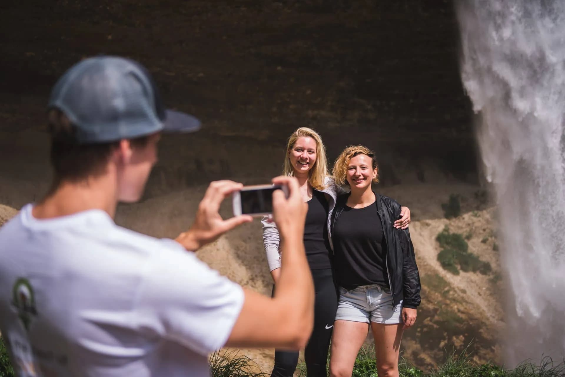 Posing for a photo next to Pericnik Waterfall with a man taking the picture.