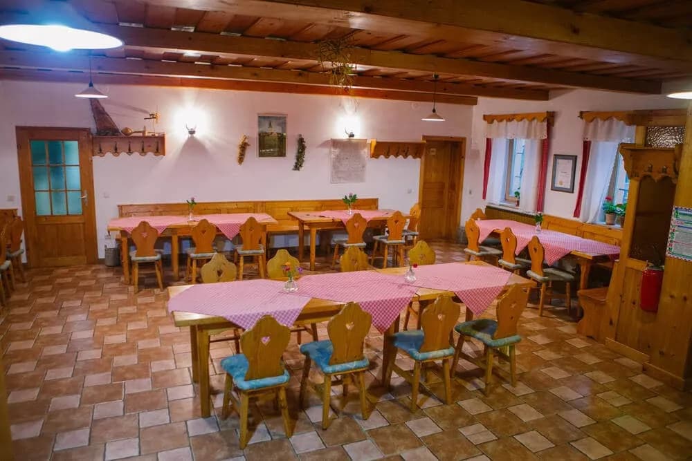 Rustic dining area with wooden tables, heart-backed chairs, and pink gingham tablecloths.