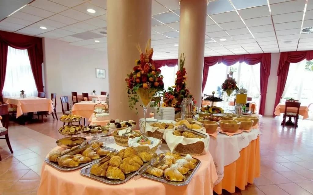Breakfast buffet with pastries, fruit, and flowers in a dining room at Hotel Marko