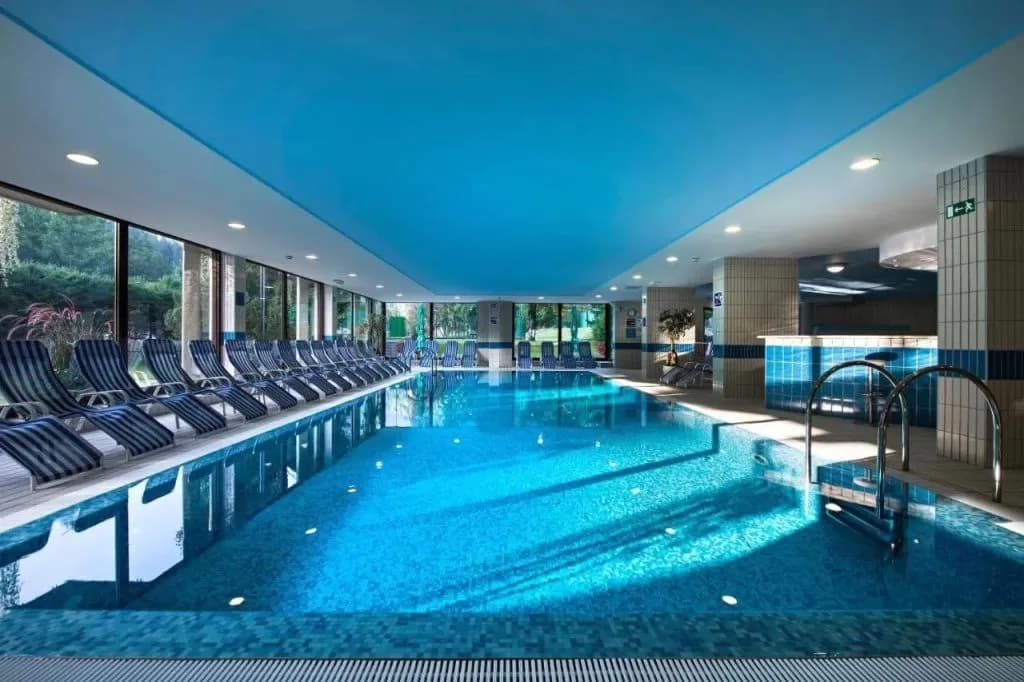 Indoor swimming pool at Best Western Kranjska Gora with blue tiled water and lounge chairs.