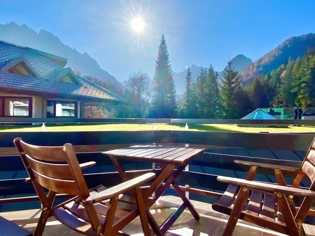 Wooden chairs and table on a terrace overlooking mountains at Best Western Kranjska Gora.