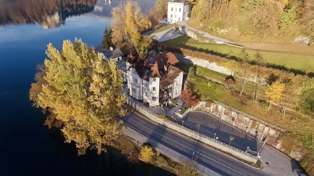 Lakeside building with autumn trees and road next to dark blue water