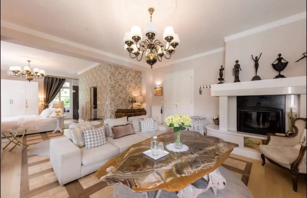Luxury living room with white sofa, ornate chandelier, fireplace, and unique stone coffee table.