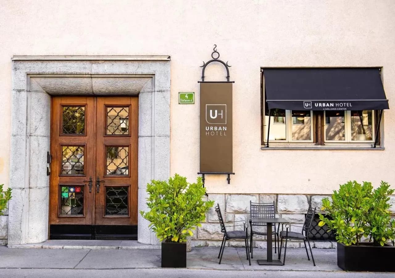 Urban Hotel exterior entrance with wooden door, outdoor seating, and Ljubljana Center sign.