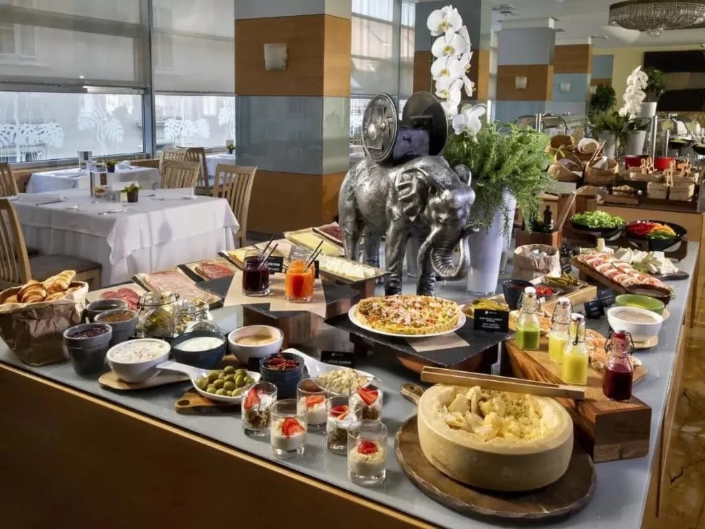 Extensive breakfast buffet with pastries, meats, cheese wheel, and drinks inside Hotel Slon.