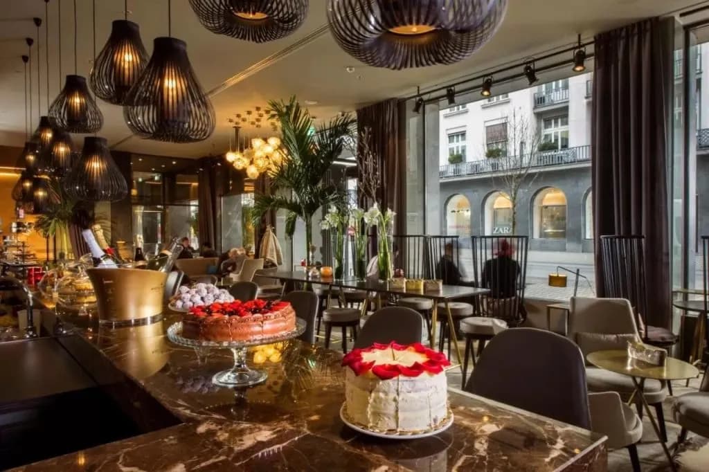 Bar counter display with cakes, champagne bucket, and modern lighting in a hotel lounge.