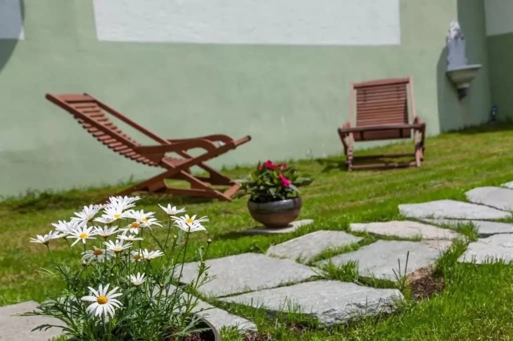 Adora Hotel atrium garden with daisies, stone path, and wooden lounge chairs.