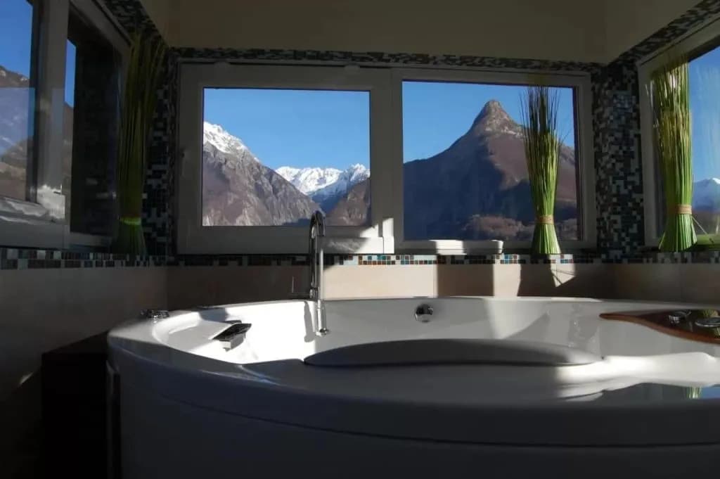 Jetted bathtub with view of snow-capped Mangart mountain range through window