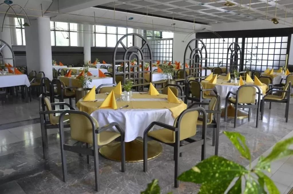 Hotel dining room set with yellow tablecloths, white linens, and yellow napkins.