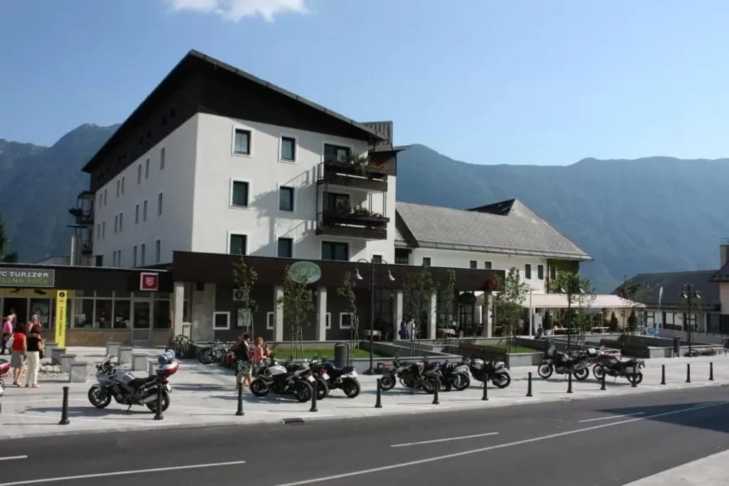 Alpine hotel with motorcycles parked outside, set against large mountains in summer