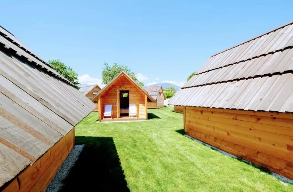 Wooden glamping houses with shingled roofs on a grassy field at Pr Mihovc Zgornja Dobrava.
