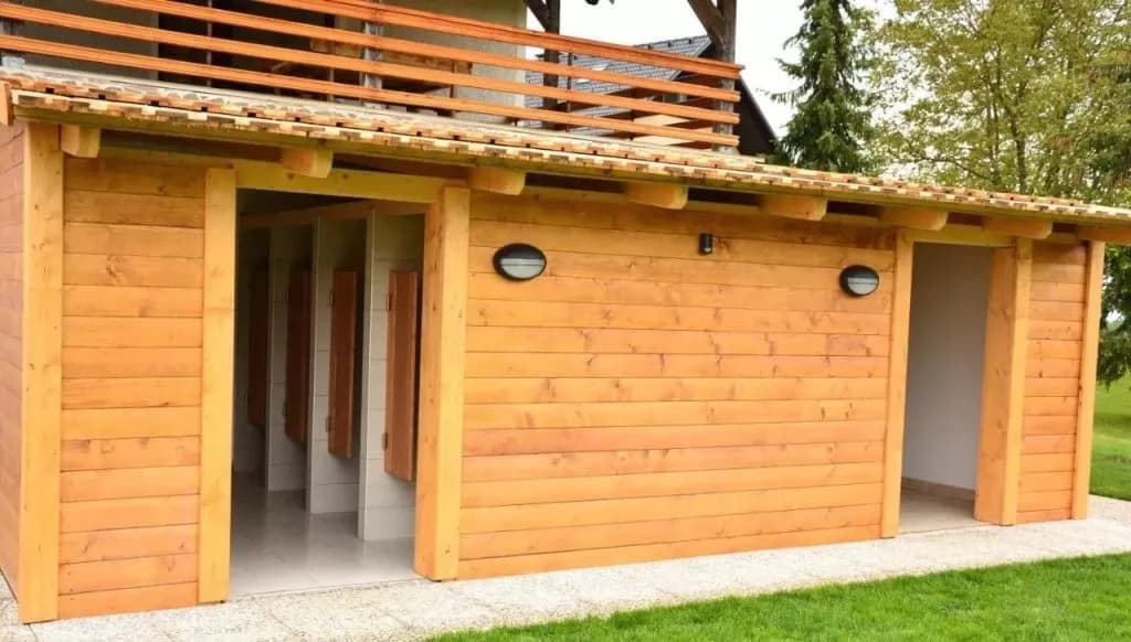 Wooden glamping facility service building with open doorways and exterior lighting in Zgornja Dobrava.