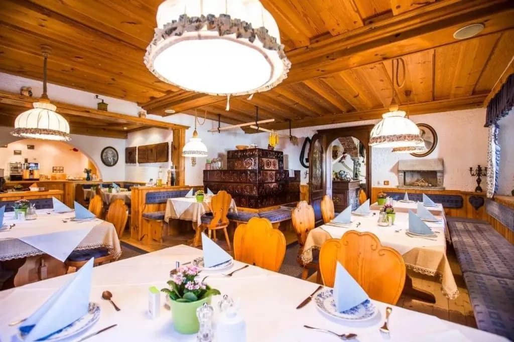 Breakfast area with wood paneling, set tables, and a traditional tiled stove at Penzion Berc.