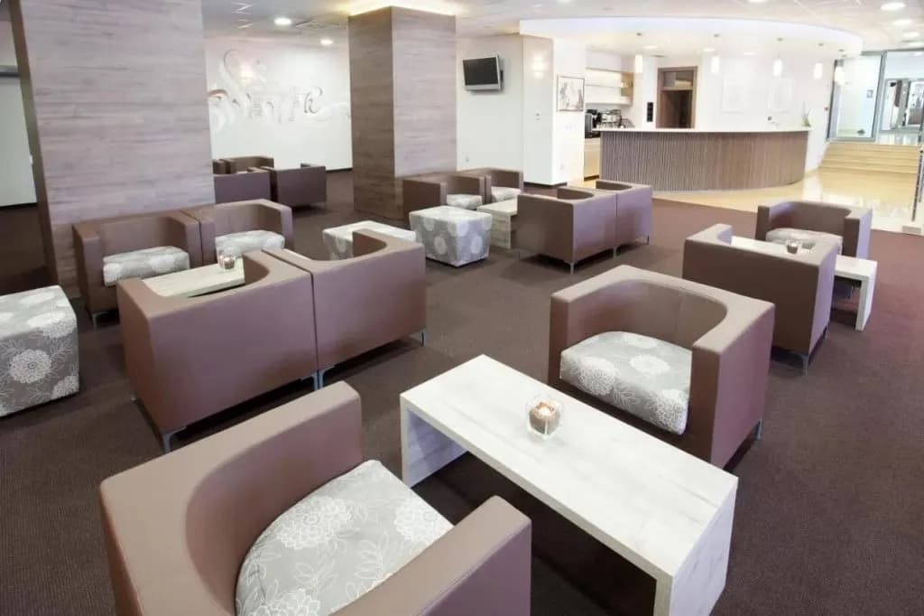 Hotel Astoria lobby with modern brown seating, patterned cushions, white tables, and a reception desk.