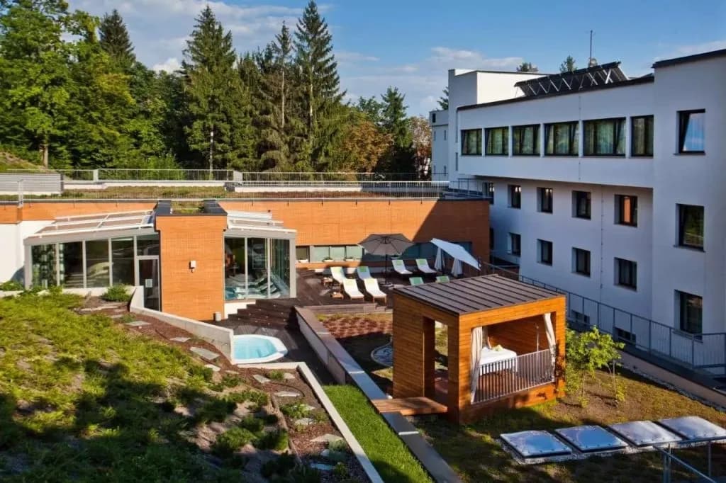 Hotel Astoria exterior with outdoor spa area, sun loungers, and surrounding forest.