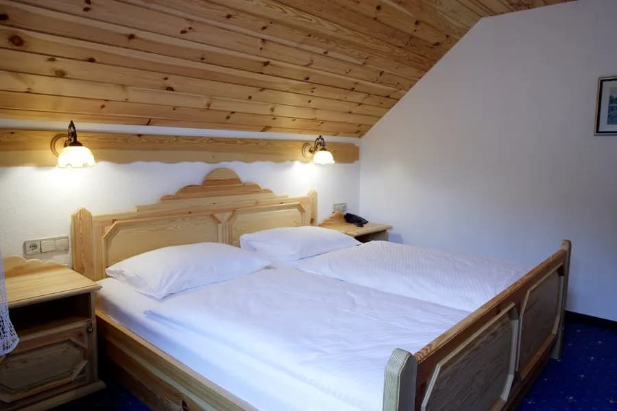 Twin beds with white linens in a room featuring wood-paneled sloped ceiling at Garni-Hotel Berc.