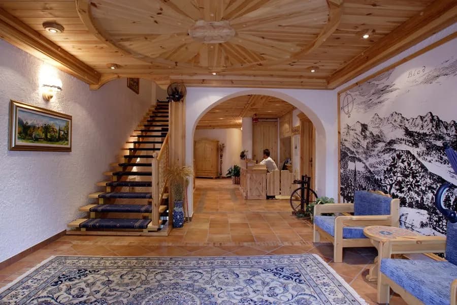 Garni-Hotel Berc lobby with wood ceiling, staircase, and mountain mural mentioning Bled