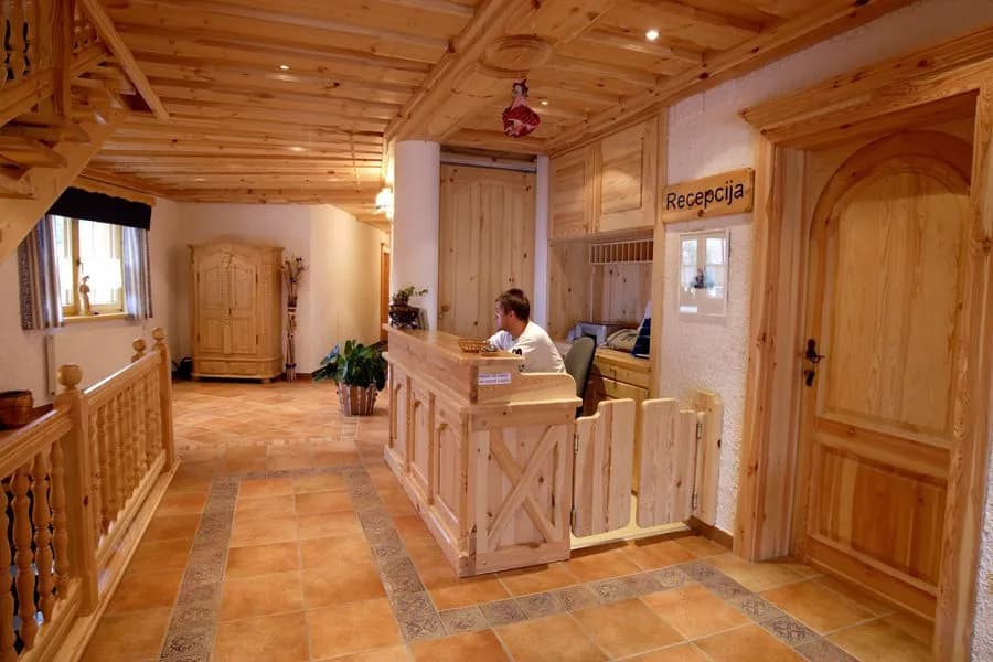 Garni Hotel Berc reception desk with wooden paneling and terracotta tile floor
