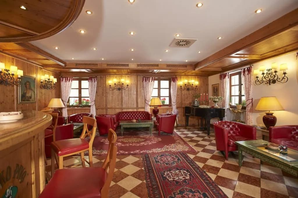 Hotel Plesnik lobby with wood paneling, red leather seating, and a black grand piano.