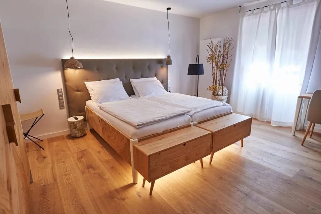 Hotel Plesnik room with twin beds, wood flooring, and bright white curtains.