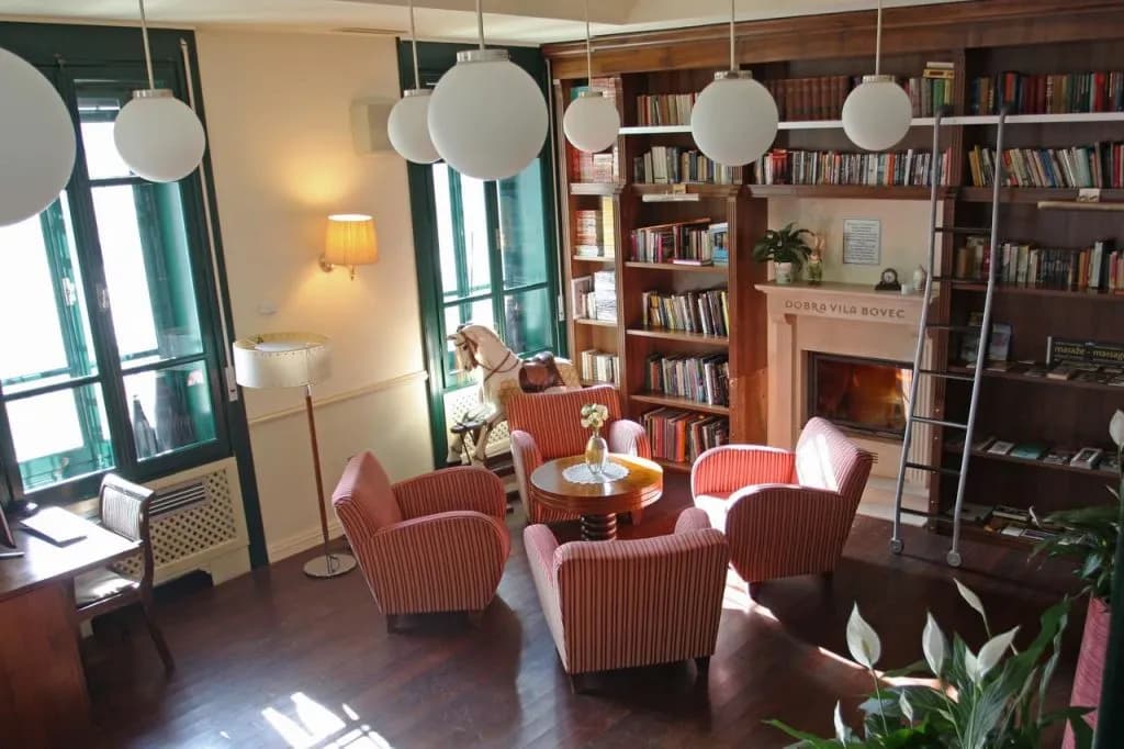 Lounge area with striped armchairs, fireplace, and built-in bookshelves at Dobra Vila Bovec.