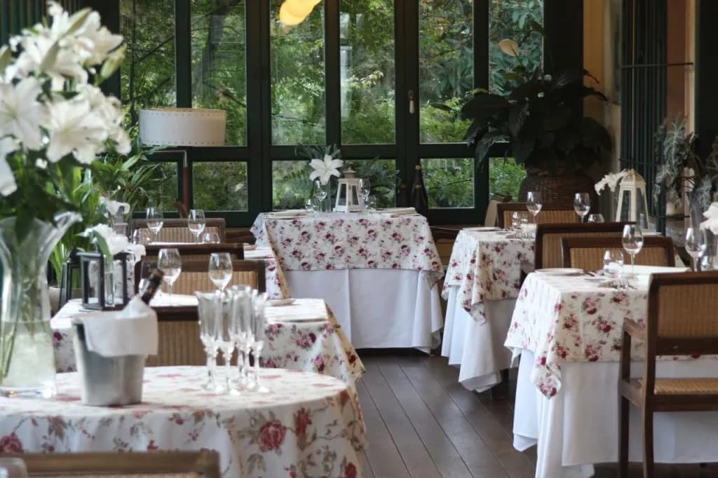 Dining area in Boutique Hotel Dobra Vila with floral tablecloths and view of lush greenery.