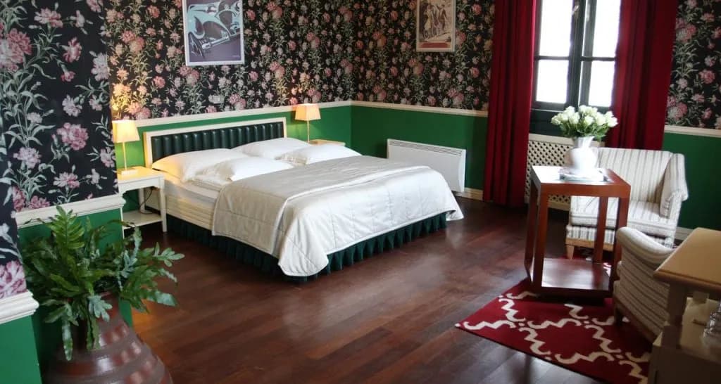 Boutique hotel room with floral wallpaper, green wainscoting, and white bedding at Boutique Hotel Dobra Vila.