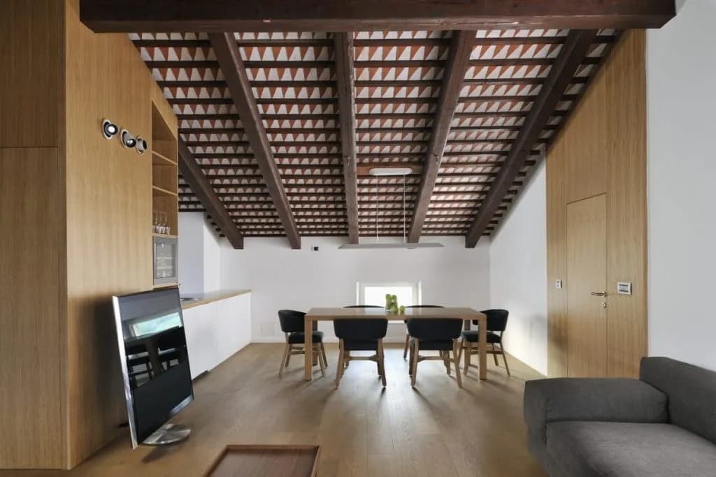 Attic suite interior with exposed wood beam ceiling, dining area, and modern wood paneling