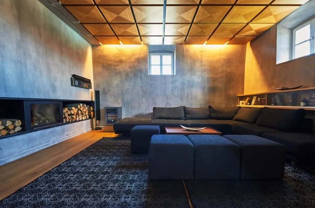 Modern living room with dark sectional, fireplace with logs, and geometric wood ceiling