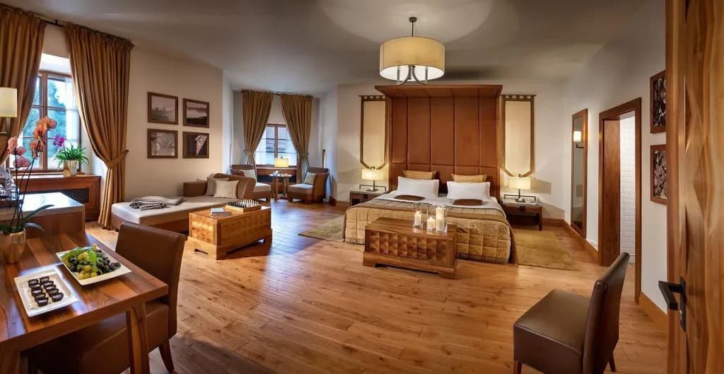 Hotel Grad Otocec suite with large bed, sitting area, and wooden floors