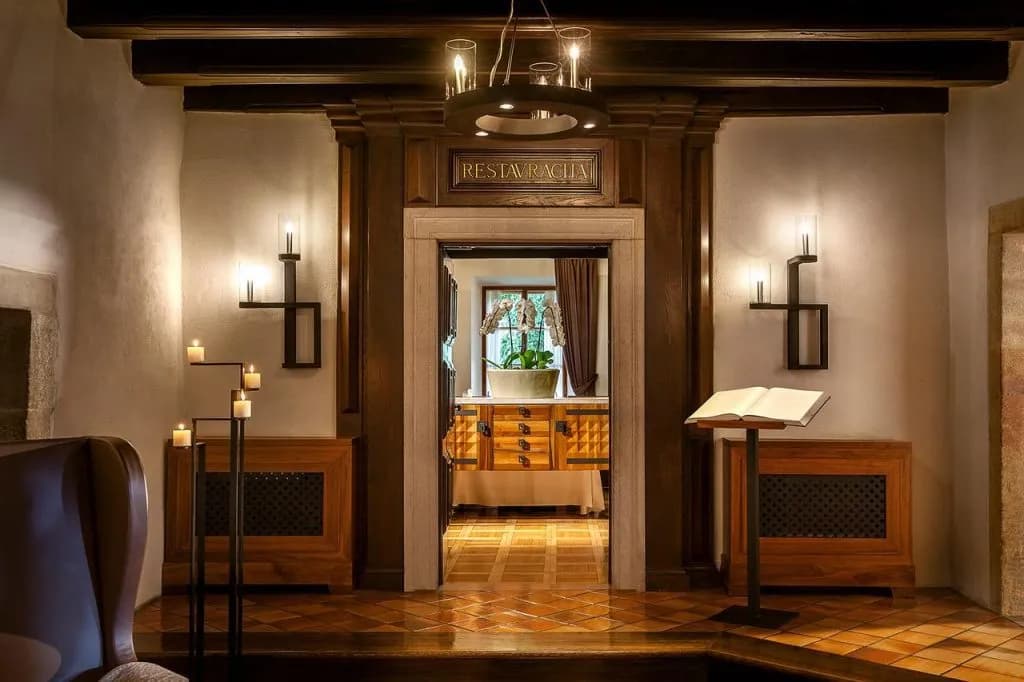 Restaurant entrance at Hotel Grad Otočec with dark wood trim, candlelight, and open book on stand.