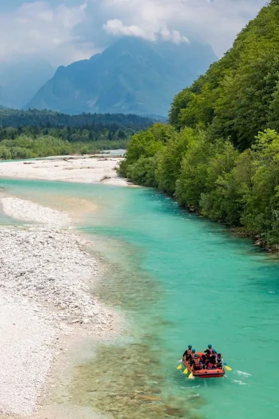 Rafting on turquoise Soca River with forested banks and mountains in background