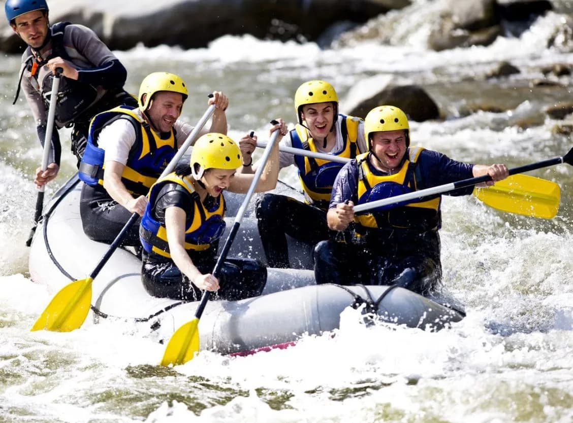 Group rafting down whitewater rapids on the Soca River wearing helmets and life vests.