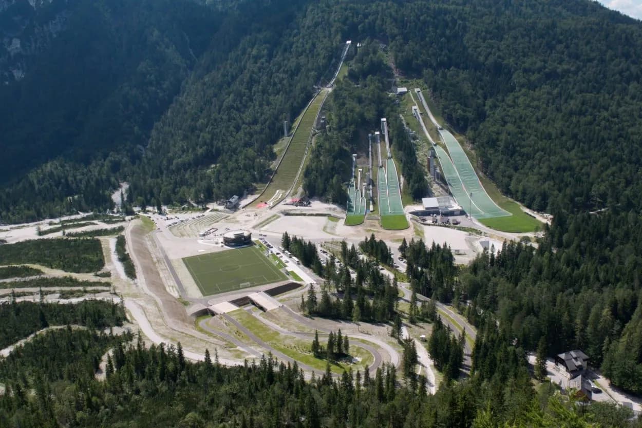 Ski jumping hills with green summer mats and a soccer field in Planica, Slovenia.