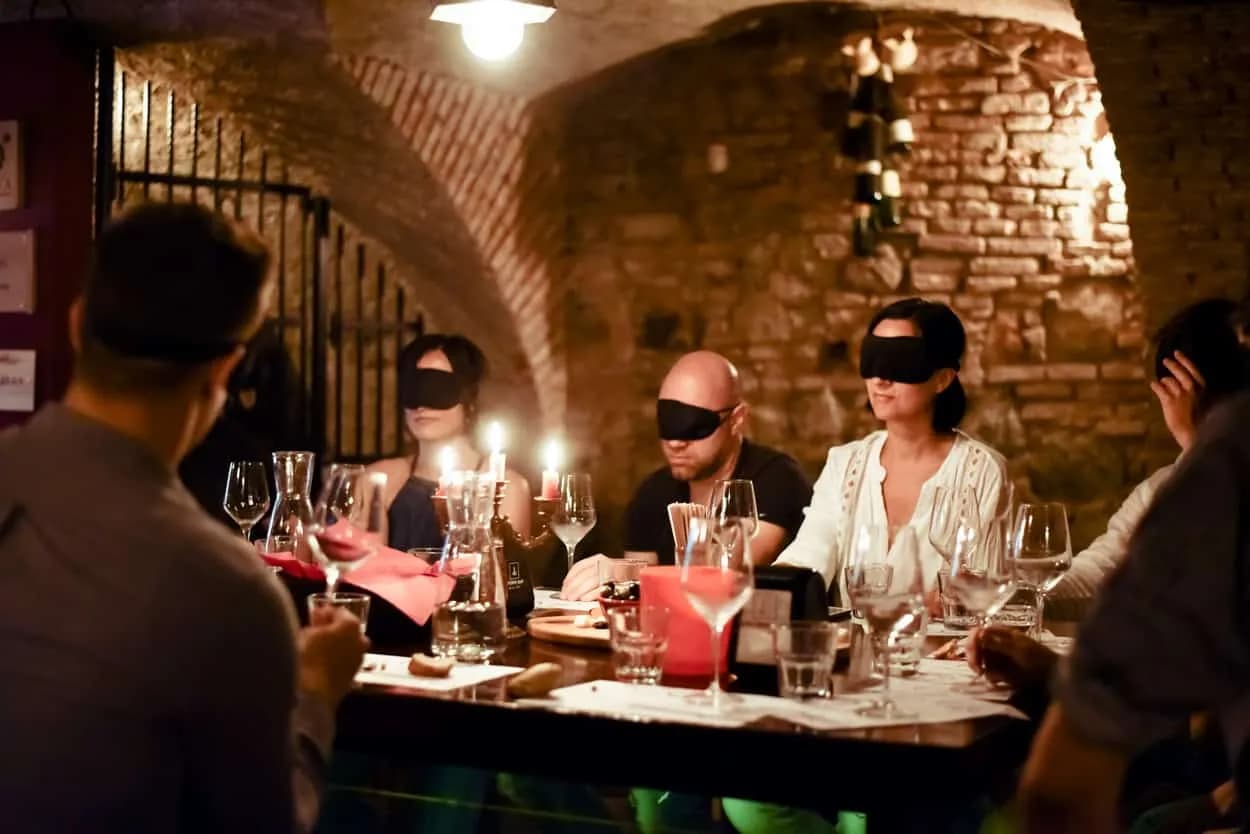 Blindfolded wine tasting event in a candlelit, vaulted brick cellar in Ljubljana.