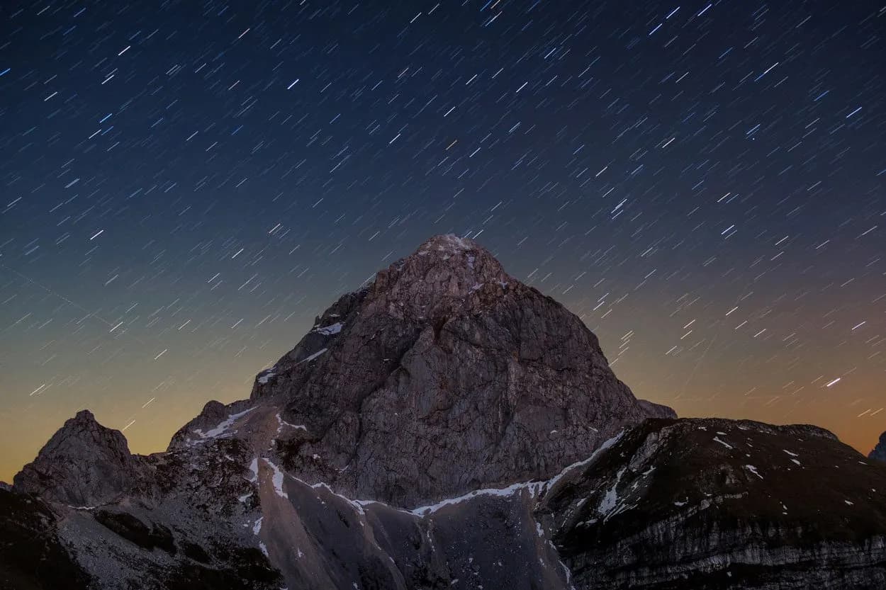 Mountain peak under star trails at night in Triglav National Park, Slovenia