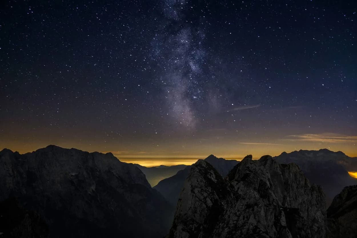 Milky Way galaxy above dark jagged mountain peaks at night in Triglav National Park