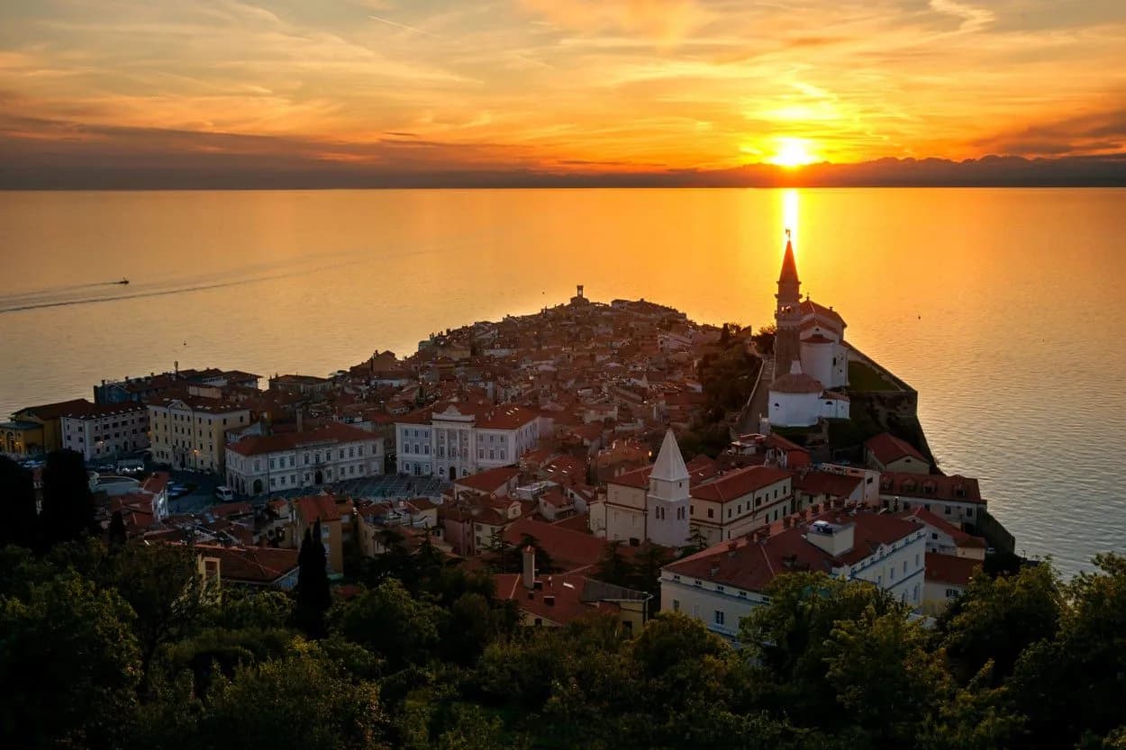 Coastal town of Piran at sunset with church spire overlooking the golden Adriatic Sea